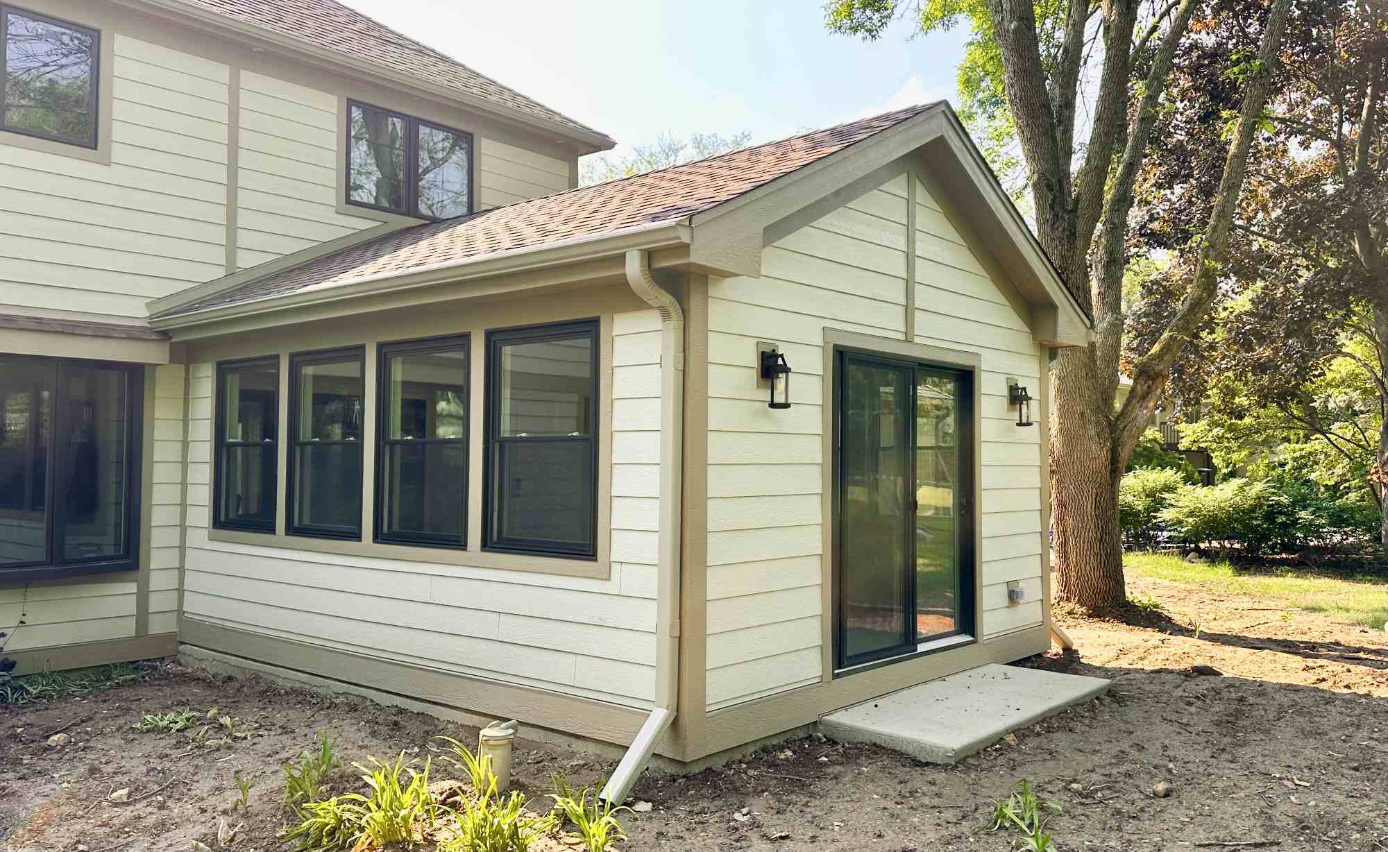 Exterior home addition by Skor Construction in Inverness, IL showcasing a completed 3 seasons room with large windows and patio -optimized