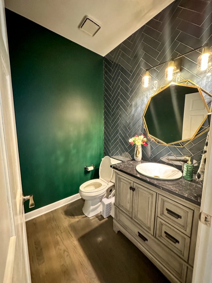 modern powder room with dark herringbone tile accent wall and custom vanity in a whole house remodel by Skor Construction in Bar-optimized