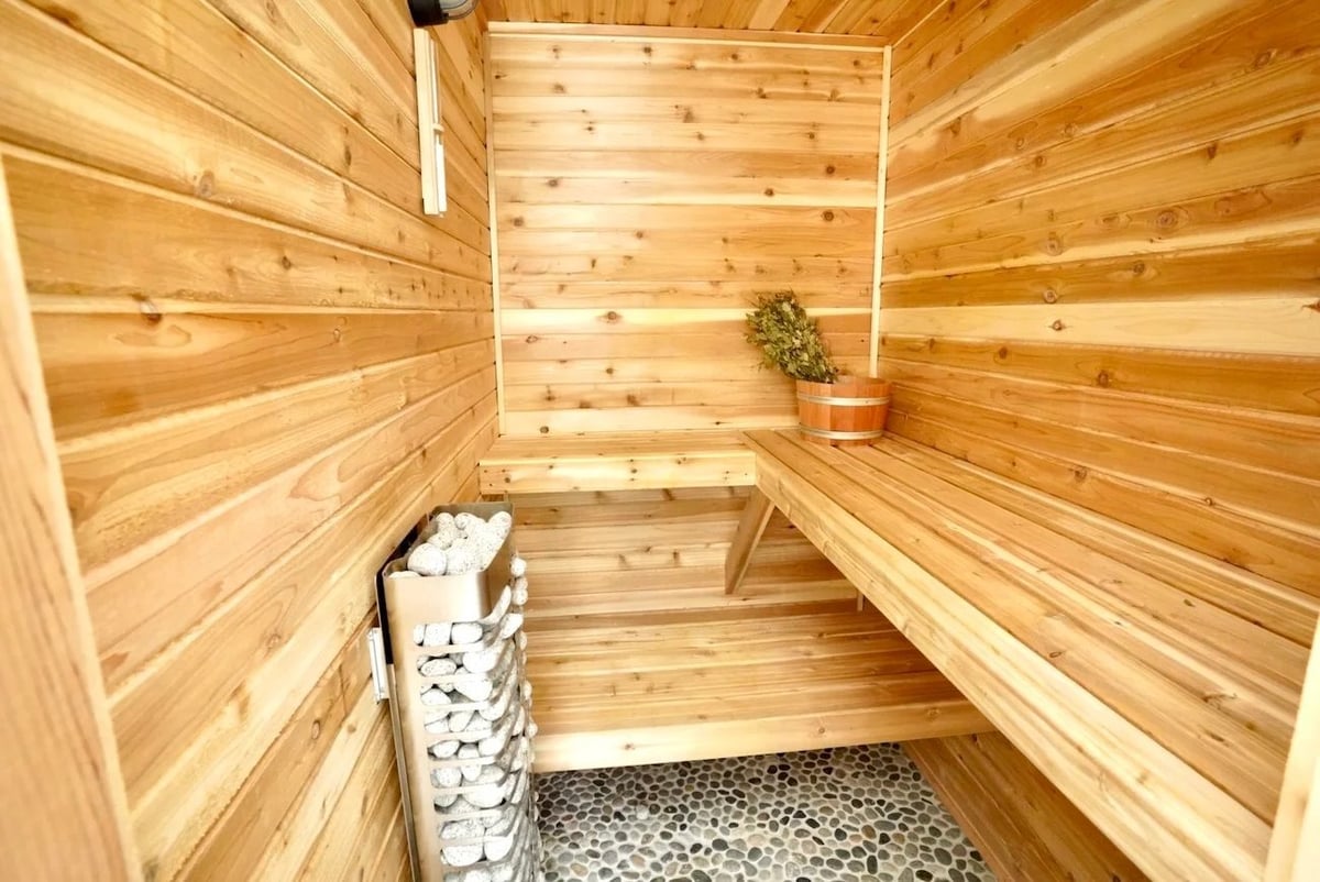 custom cedar sauna remodeling in barrington il with tiered wood benches stone heater pebble floor and wood bucket by skor construction