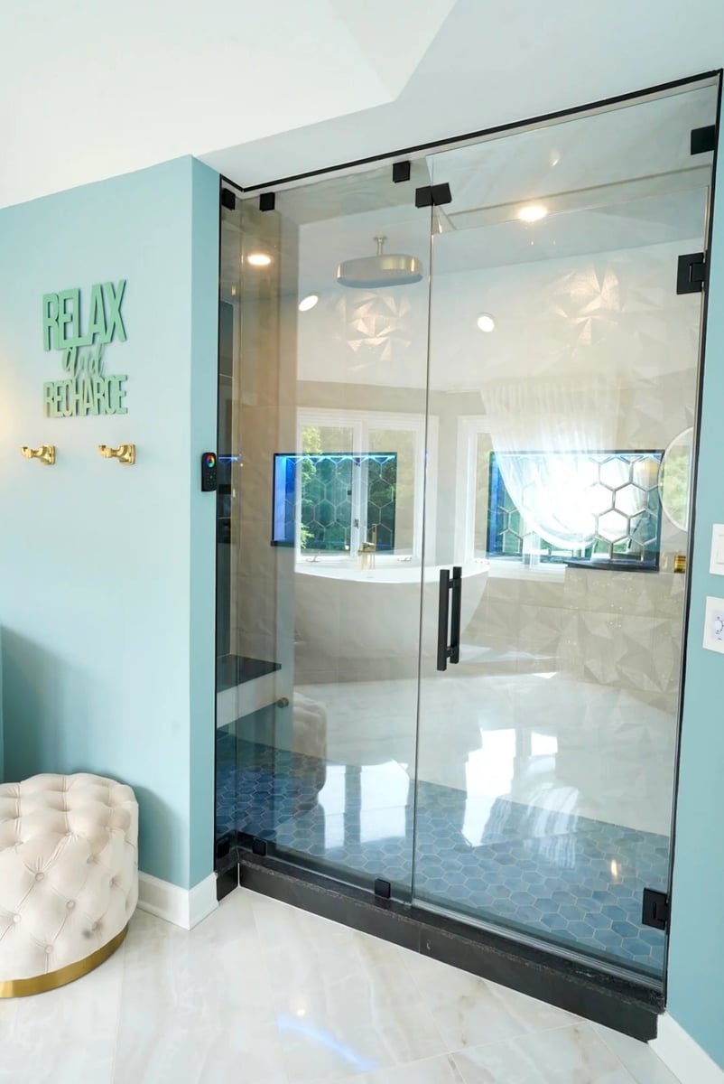 frameless glass shower enclosure bathroom remodeling project in barrington il with black hardware rain head showerhead and blue hexagon tile floor by skor construction