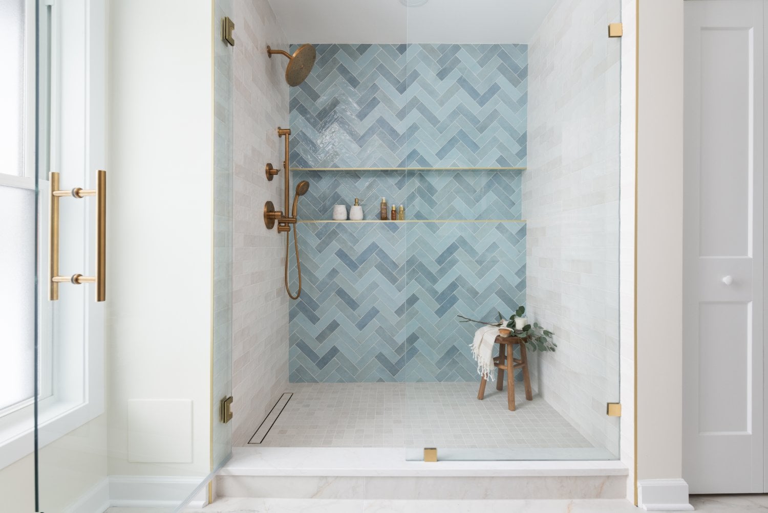 Lama primary bathroom by Skor Construction in Mount Prospect, IL featuring a walk-in shower with blue herringbone tile and brass-optimized