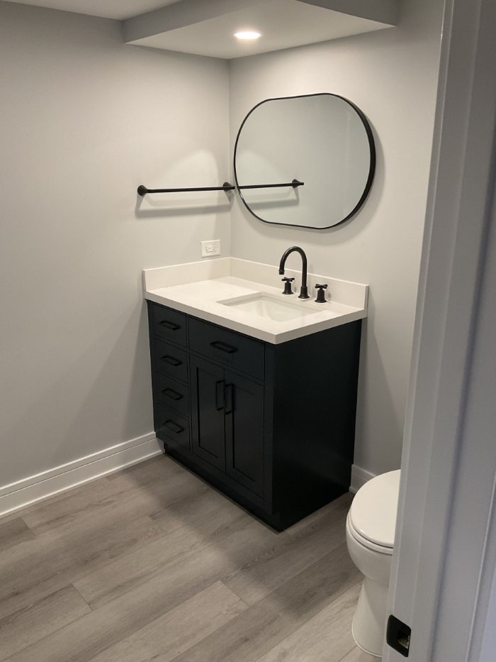 finished basement bathroom in Riverwoods, IL by Skor Construction featuring contemporary black cabinetry and gray flooring.-optimized