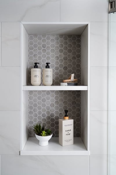 Contemporary shower storage feature by Skor Construction in Lincolnshire, IL with hexagon accent tile and marble-look walls.-optimized