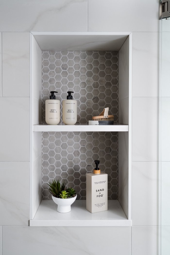 Contemporary shower storage feature by Skor Construction in Lincolnshire, IL with hexagon accent tile and marble-look walls.-optimized