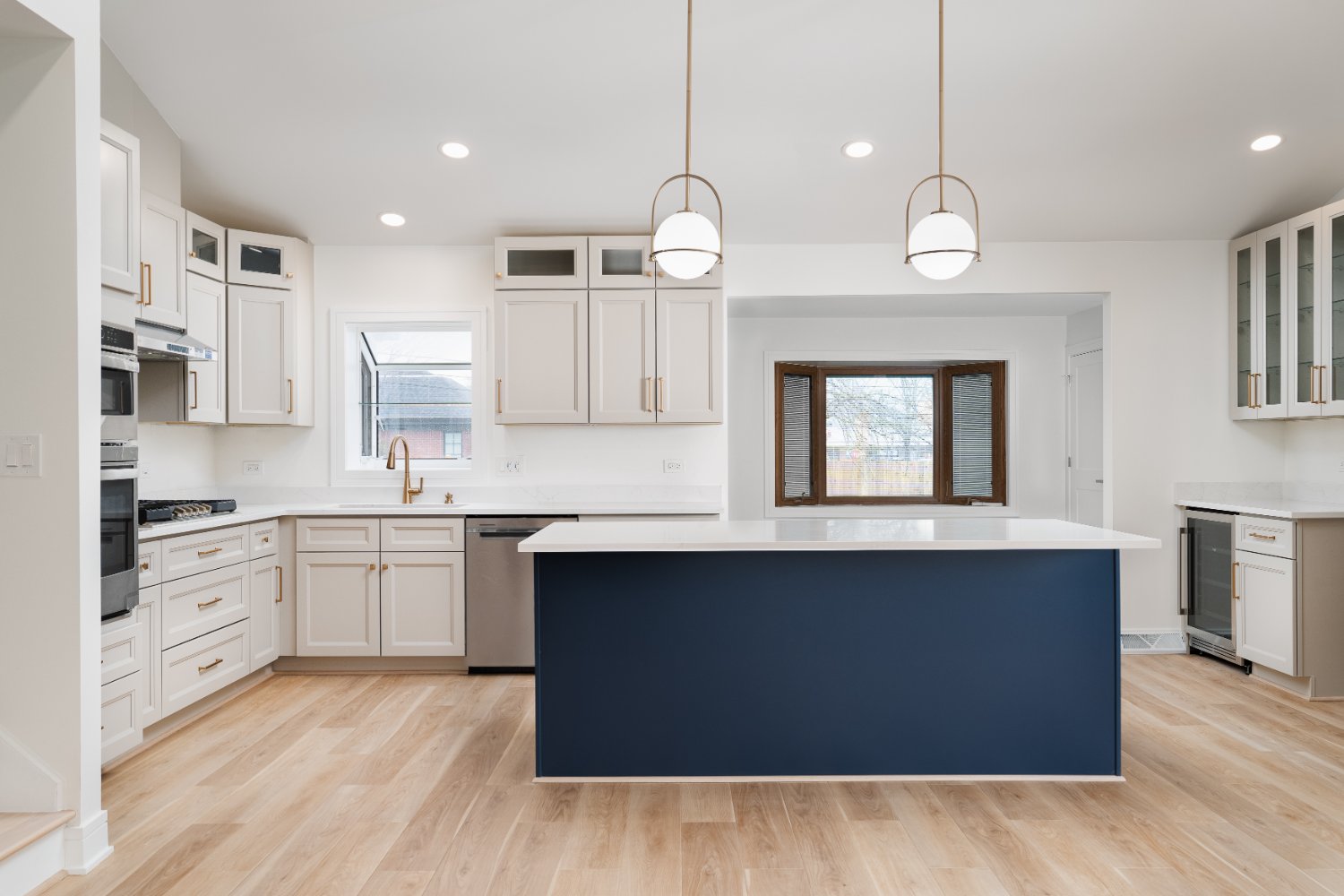 Skor Construction kitchen remodel in Arlington Heights, IL featuring a navy blue island, custom white cabinetry, and brass penda-optimized