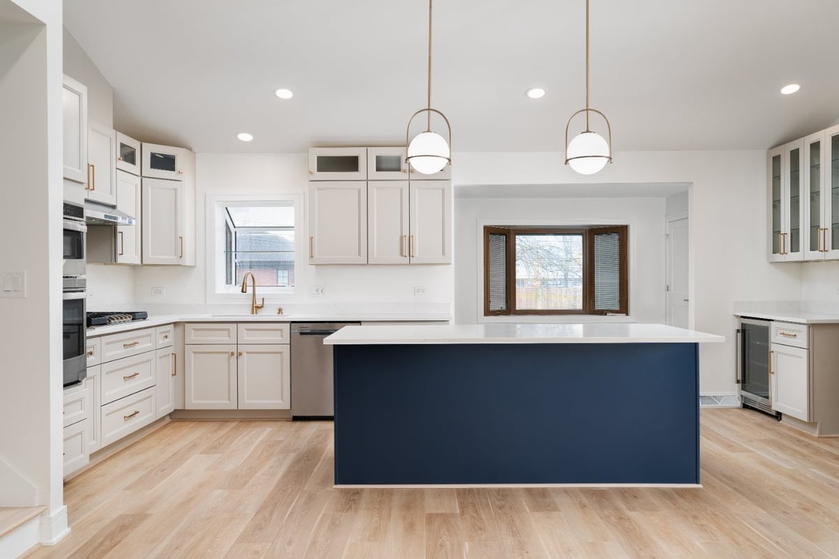 Skor Construction kitchen remodel in Arlington Heights, IL featuring a navy blue island, custom white cabinetry, and brass penda-optimized