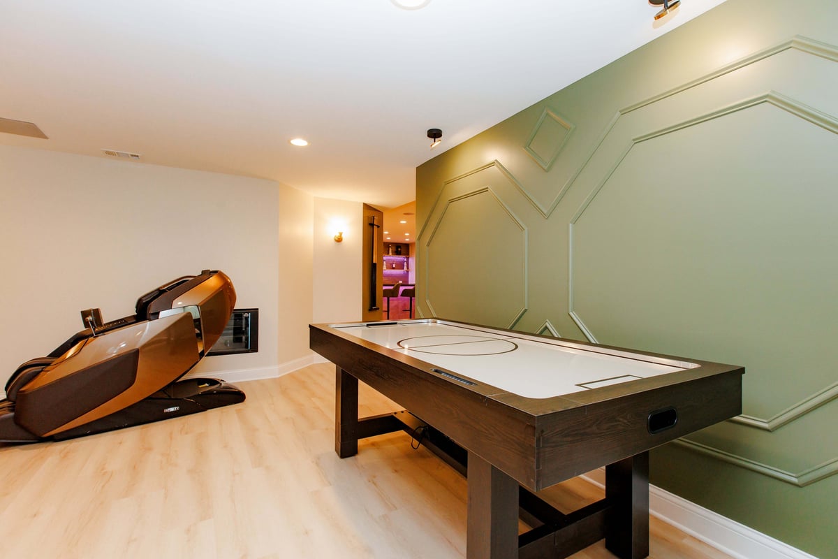 Basement game area with green wall and grim in basement remodel by Skor COnstruction