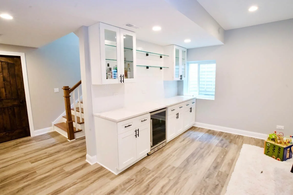 View from bottom of stairs in fished basement in North Shore with bar area with fridge