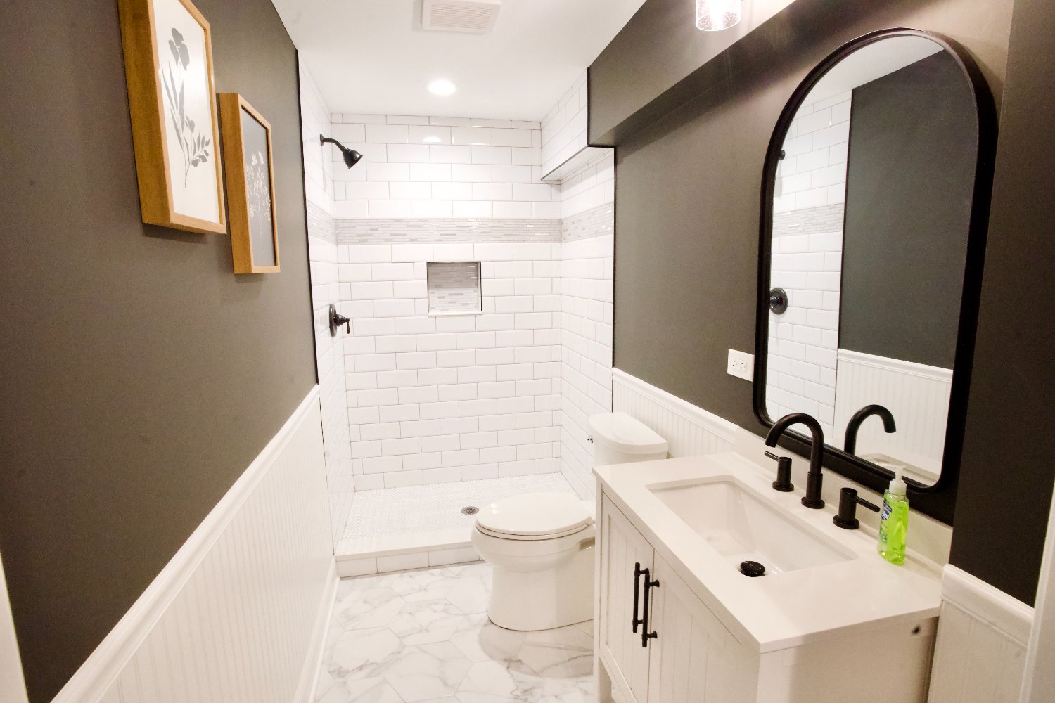 finished basement bathroom by Skor Construction in Hoffman Estates, IL with subway tile shower walls, black fixtures, and marble-optimized