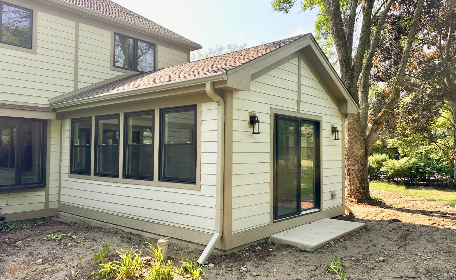 Exterior home addition by Skor Construction in Inverness, IL showcasing a completed 3 seasons room with large windows and patio -optimized