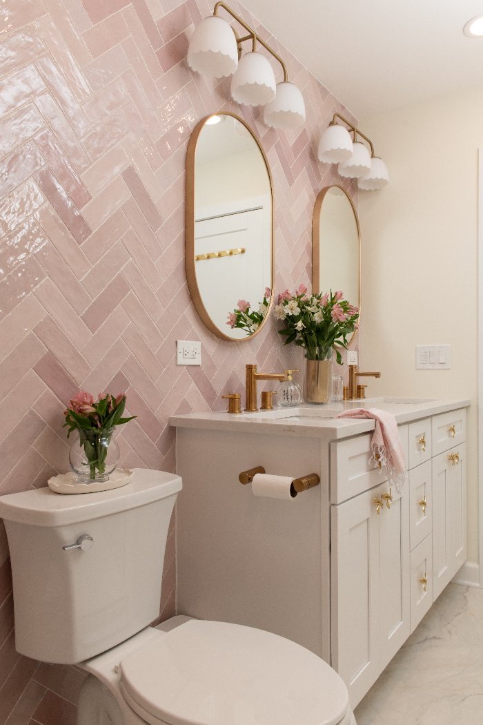 stylish blush bathroom interior by Skor Construction in Mount Prospect, IL featuring white shaker cabinets and brass fixtures.-o