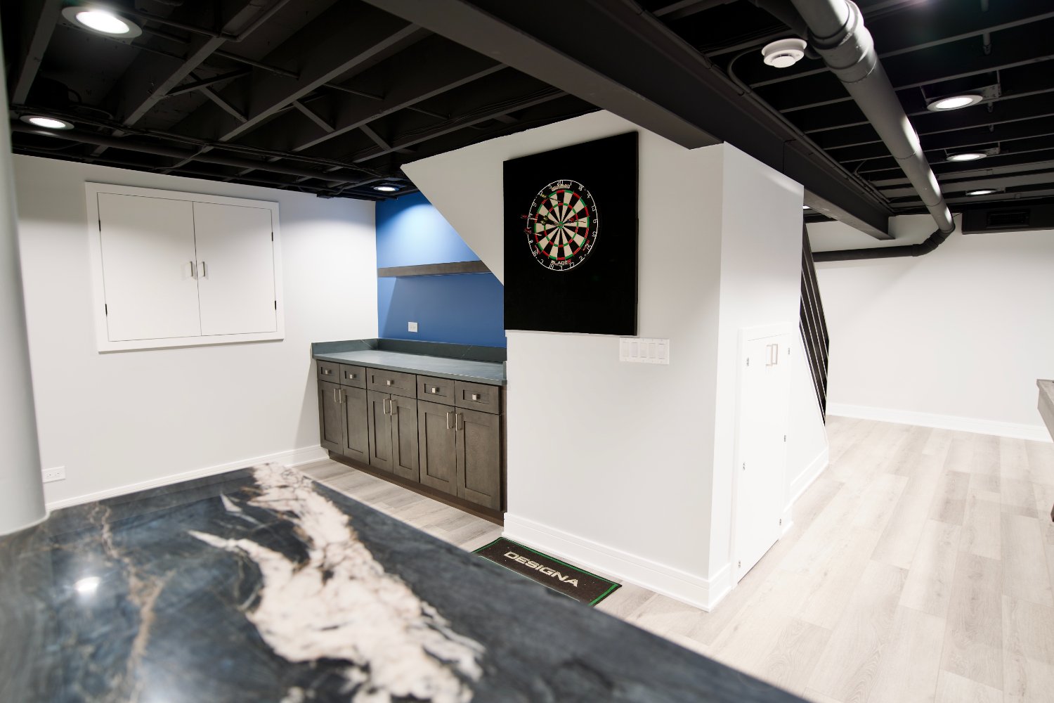 luxury finished basement in Riverwoods, IL by Skor Construction featuring dark wood cabinets and bright flooring.-optimized