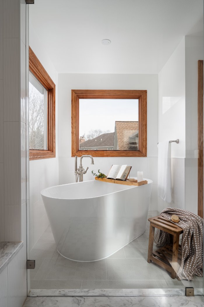 Skor Construction Lauder Primary Bathroom Remodel in Inverness, IL featuring a freestanding tub beneath large wood-trimmed windo-optimized