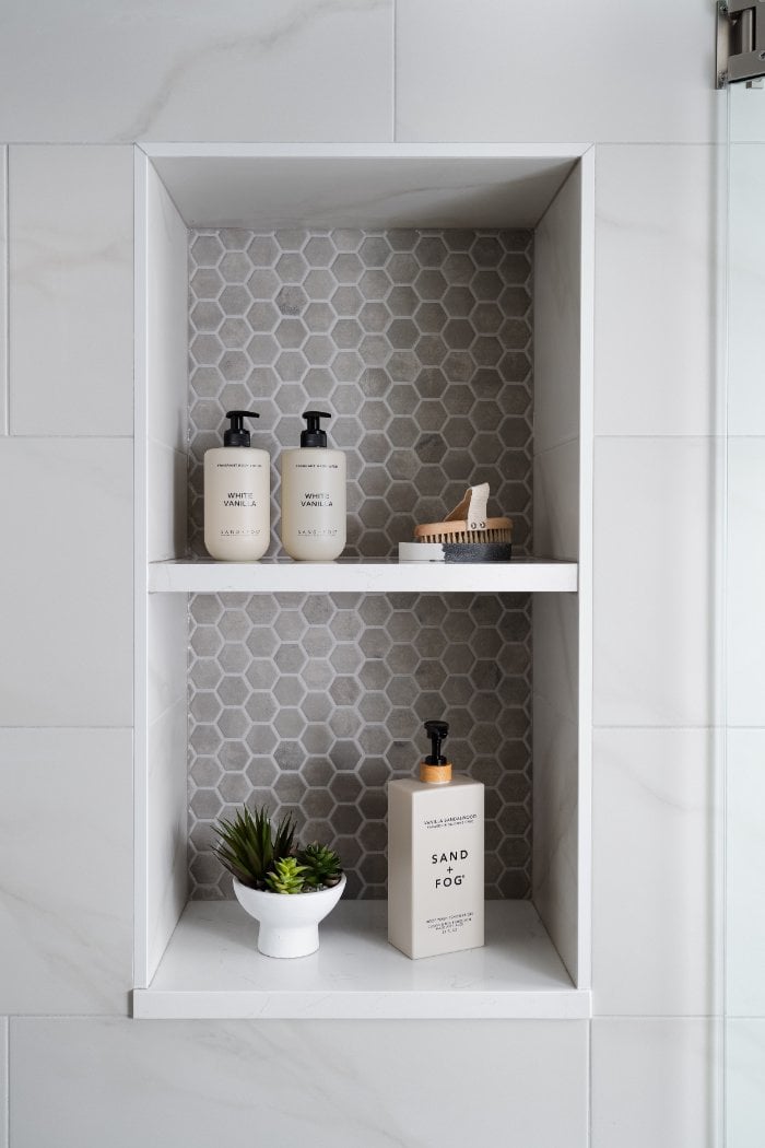 Contemporary shower storage feature by Skor Construction in Lincolnshire, IL with hexagon accent tile and marble-look walls.-optimized