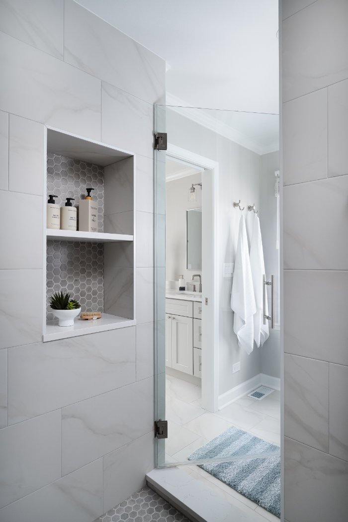 Modern primary bathroom shower detail by Skor Construction in Lincolnshire, IL with built-in shelving and sleek tile finishes.-optimized