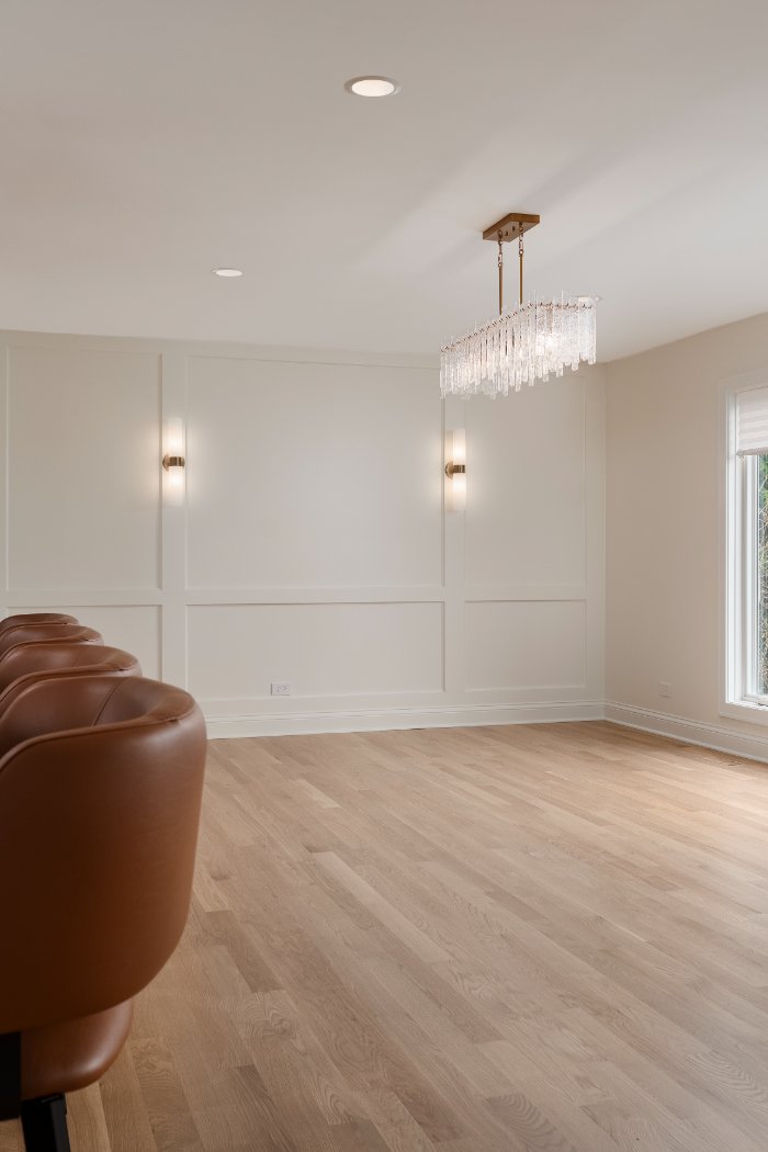 Bright open dining space remodel by Skor Construction in Mount Prospect, IL with elegant sconces, custom wall trim, and contempo-optimized