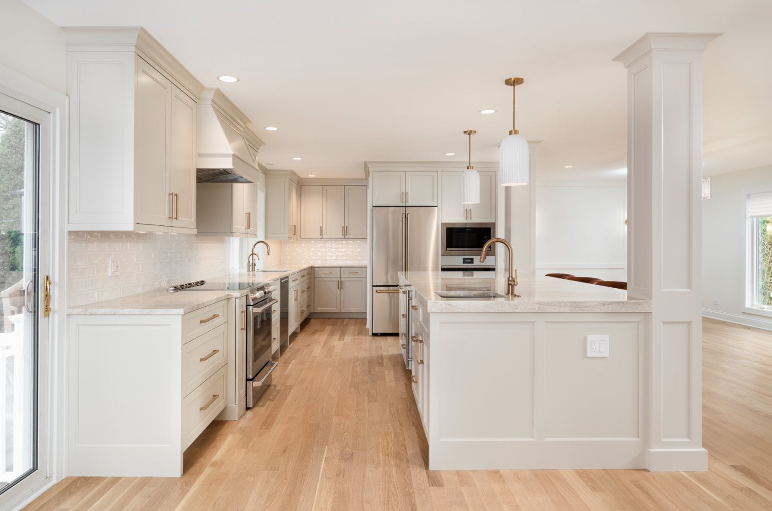 Open-concept kitchen remodel by Skor Construction in Mount Prospect, IL featuring brass fixtures, custom cabinetry, and hardwood-optimized