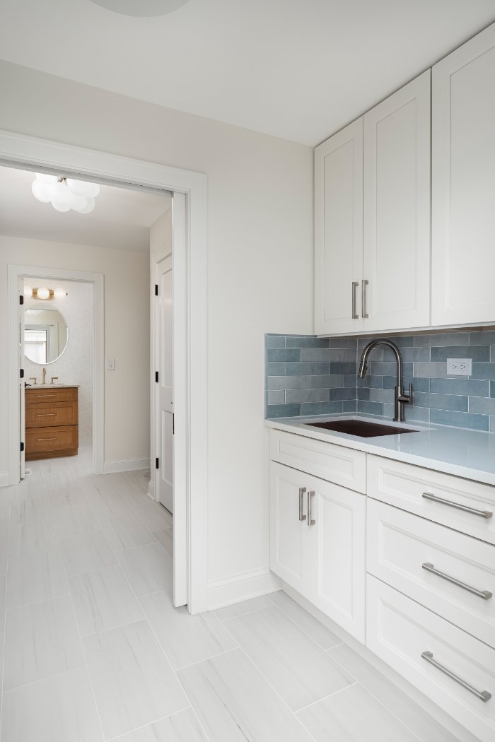 Skor Construction laundry room renovation in Mount Prospect, IL featuring custom white cabinetry, blue subway tile backsplash, a-optimized