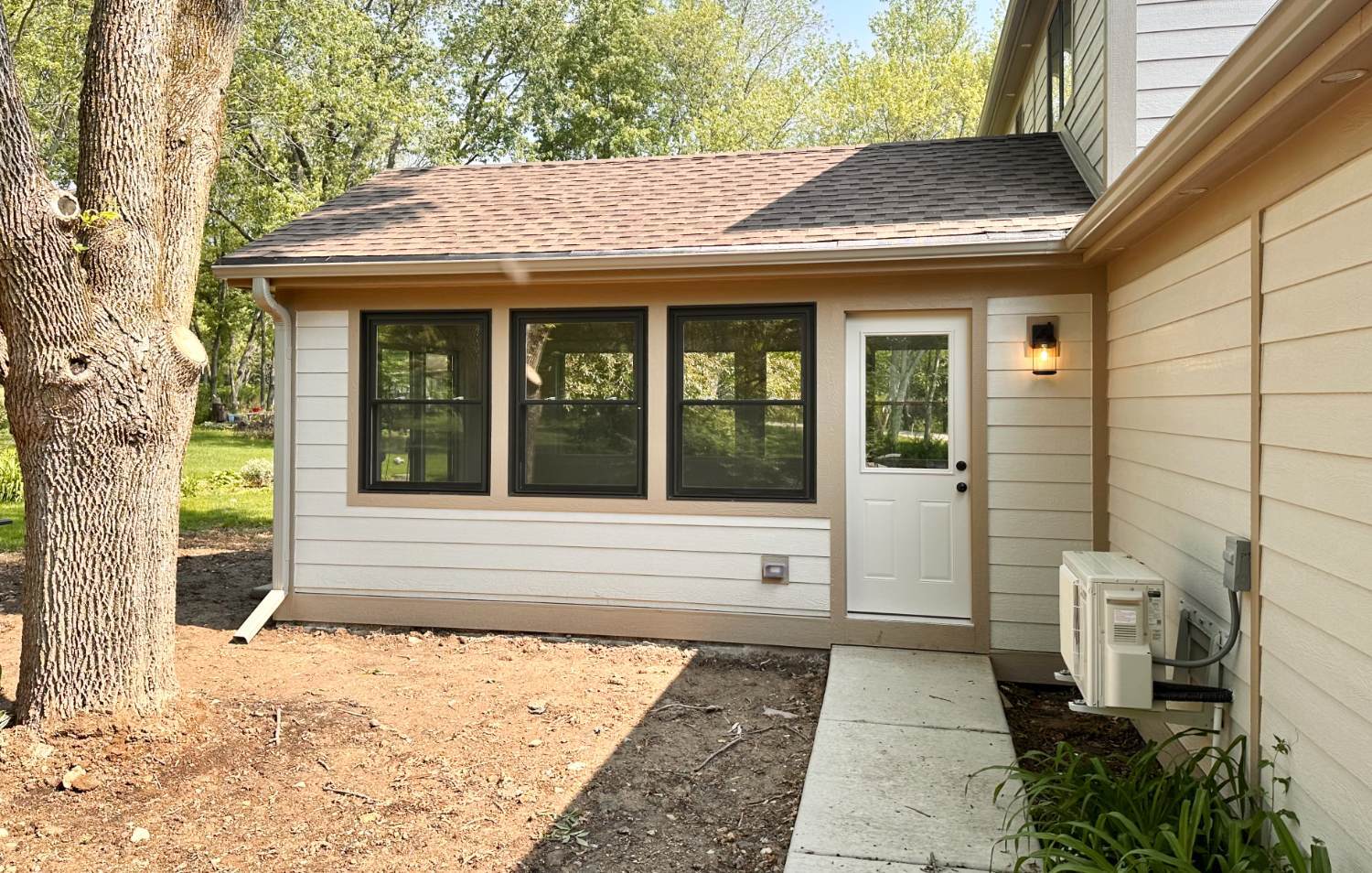 Exterior 3 seasons room addition by Skor Construction in Inverness, IL featuring new siding, black framed windows, and exterior